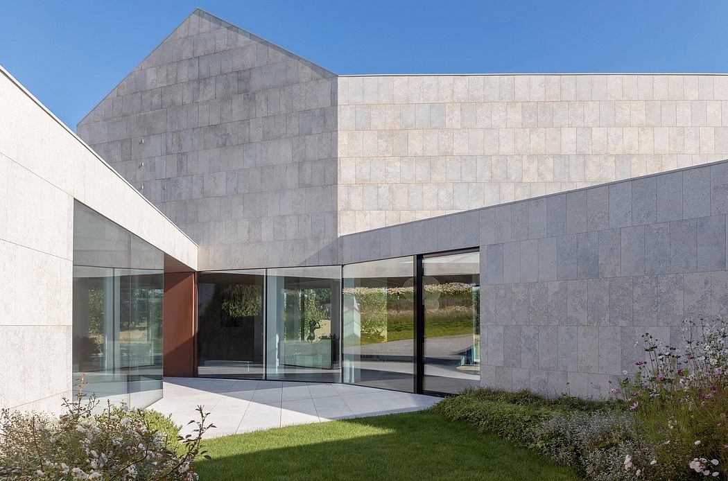 A modern architectural design with large glass windows, natural stone cladding, and landscaped garden.