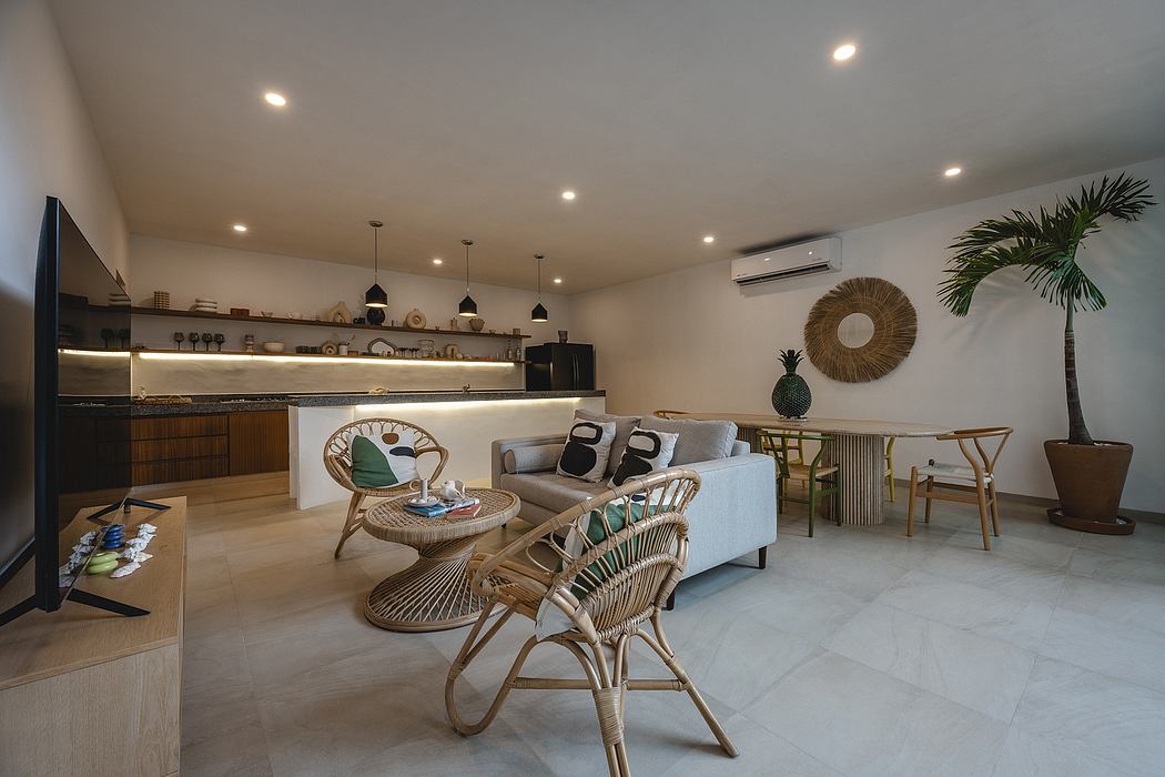Spacious, light-filled living area with rattan furniture, tropical accents, and modern kitchen.