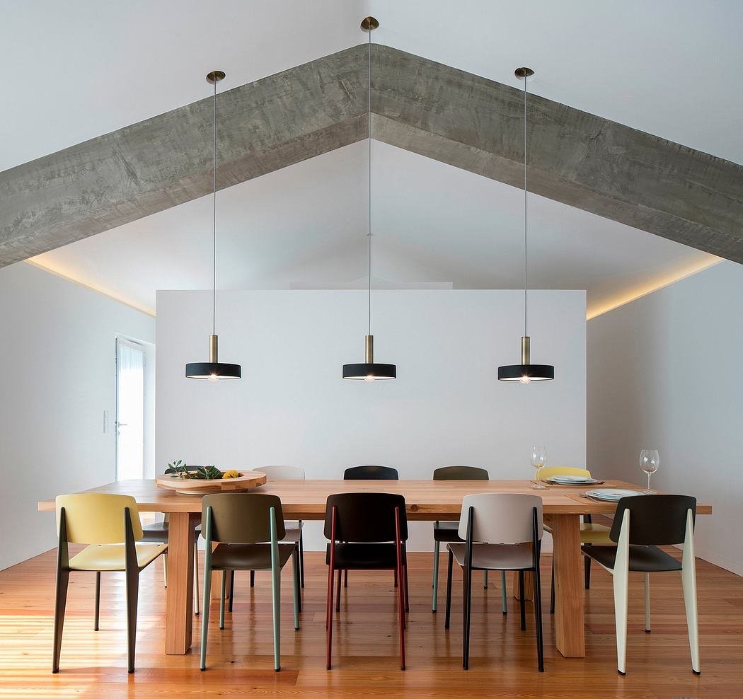 A modern dining room with a wooden table, geometric pendant lights, and concrete ceiling beams.