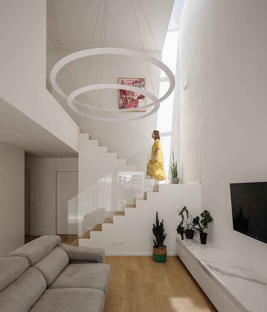 Sleek, minimalist interior with modern floating stairs, circular light fixtures, and plants.