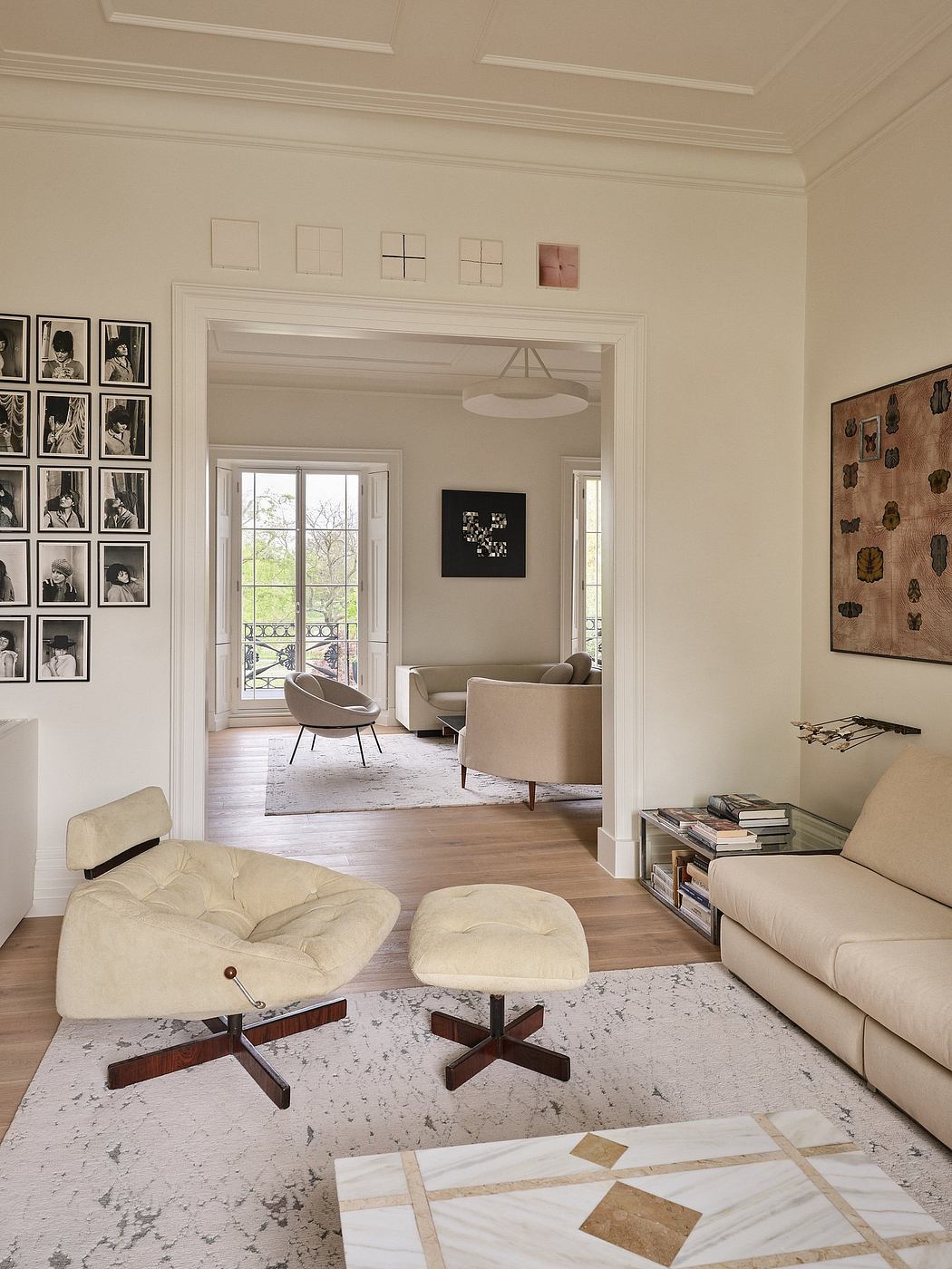Elegant living room with ornate moldings, large windows, and a curated gallery wall.