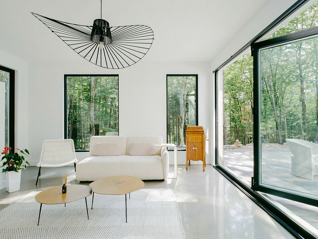 Minimalist living room with sleek furniture, large windows, and a sculptural pendant lamp.