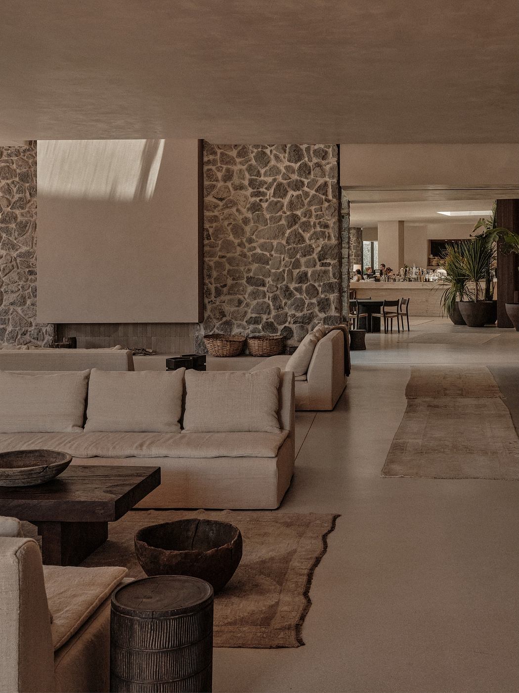 Minimalist living room with stone walls, neutral-toned furnishings, and natural textures.