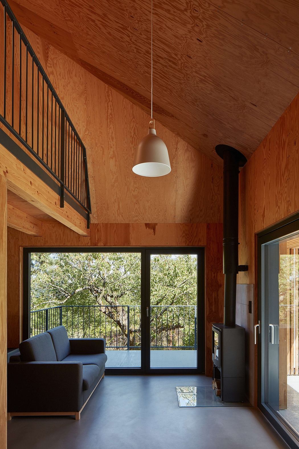 A cozy, wood-paneled room with black furniture, a large window, and a hanging light fixture.