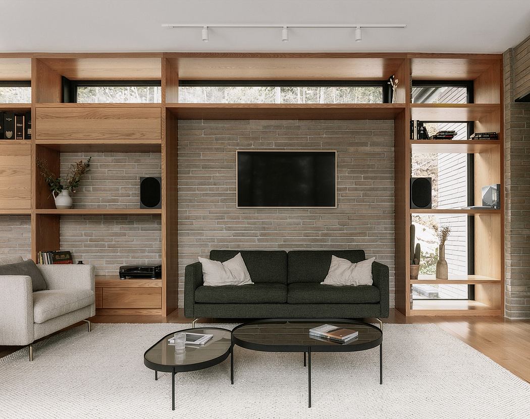 A modern living room with a built-in entertainment unit, brick accent wall, and minimalist furnishings.