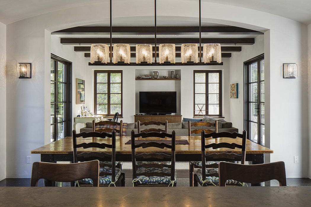 A rustic dining room with a vaulted ceiling, wooden beams, and chandelier lighting.