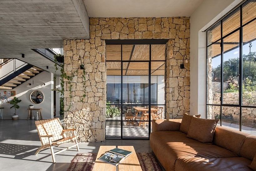 Modern, open-concept interior with stone walls, large windows, and comfortable furniture.