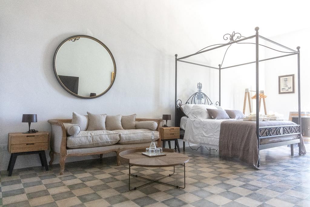 Cozy living room with plush sofa, ornate bed, round coffee table, and checkered tile floor.