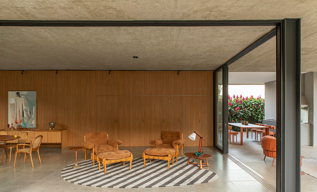 Warm wooden paneling, midcentury-inspired furniture, and expansive glass doors create a cozy and inviting space.