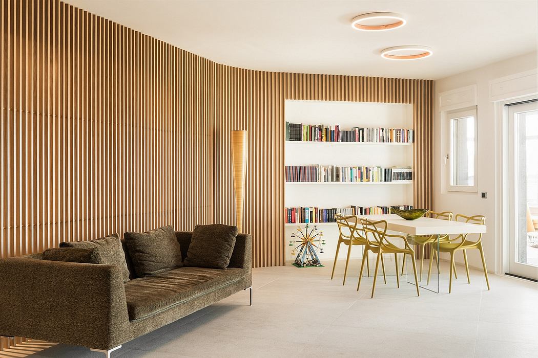 Modern open-plan living room with wood paneled walls, built-in shelving, and minimalist decor.