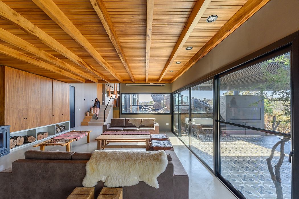 Spacious open-plan living area with wooden beamed ceiling, large windows, and cozy seating.