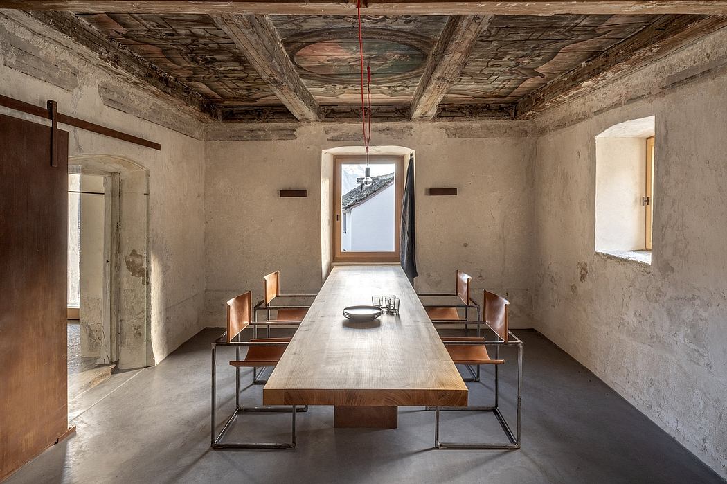 Rustic dining room with ornate wooden ceiling, large table, and minimalist bench seating.