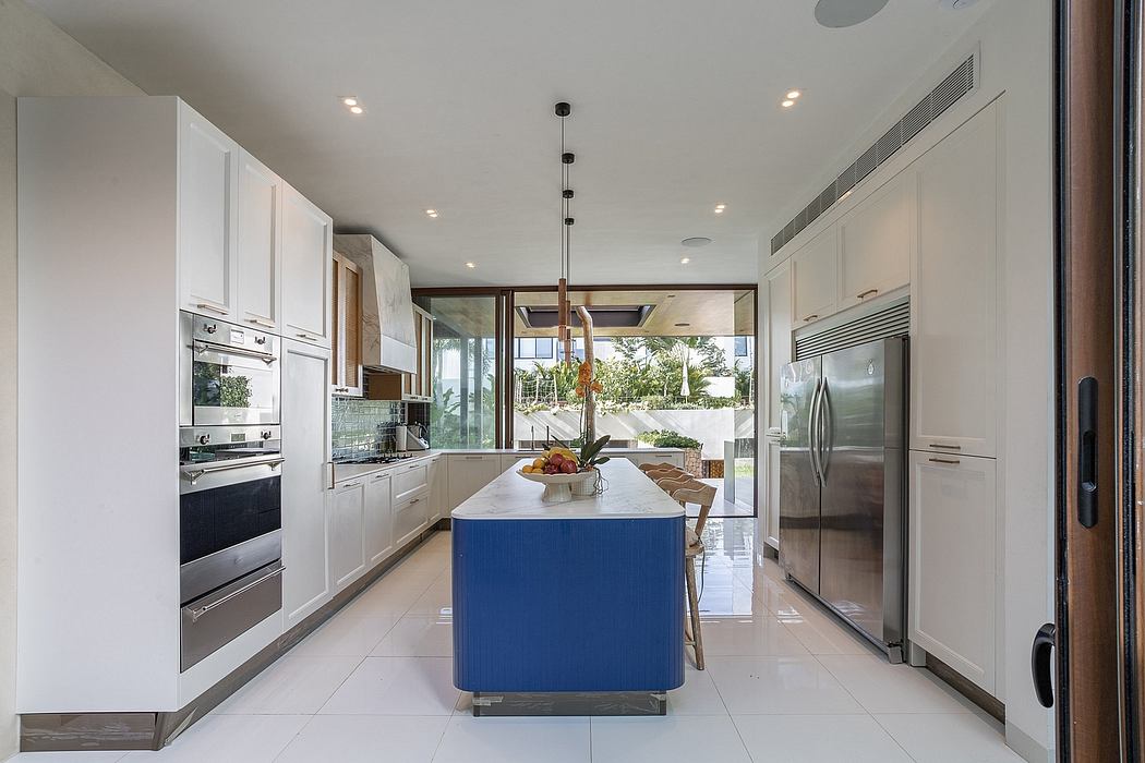 Spacious, modern kitchen with stainless steel appliances, white cabinets, and a blue island.