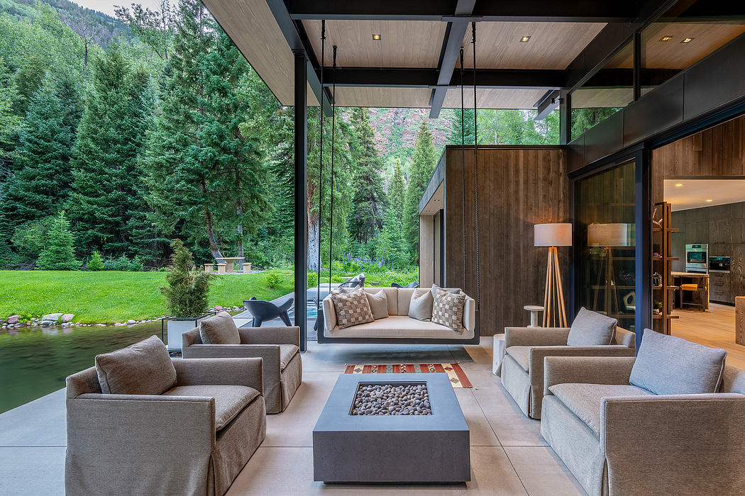 Expansive glass walls overlook a lush forest, with a cozy living room arrangement.