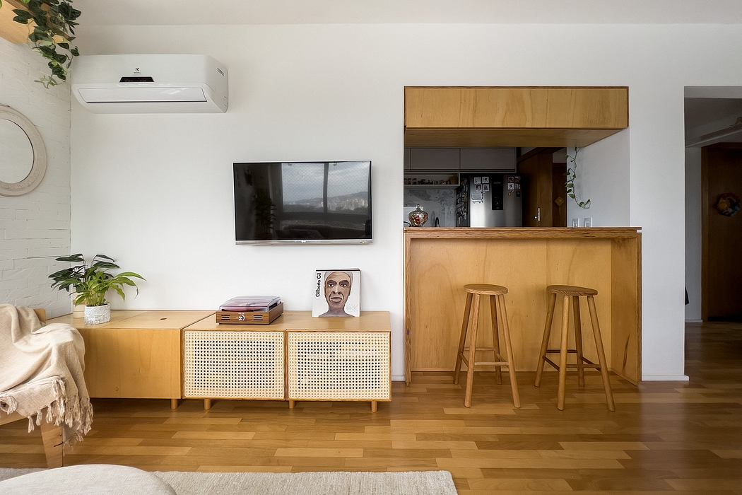 Minimalist living room with wooden furniture, built-in shelves, and a TV on the wall.