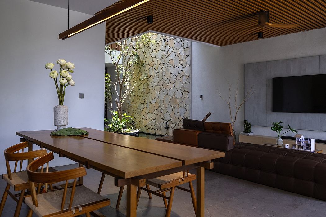 The image showcases a modern, open-concept living space with a wooden dining table, leather sofa, and stone accent wall.