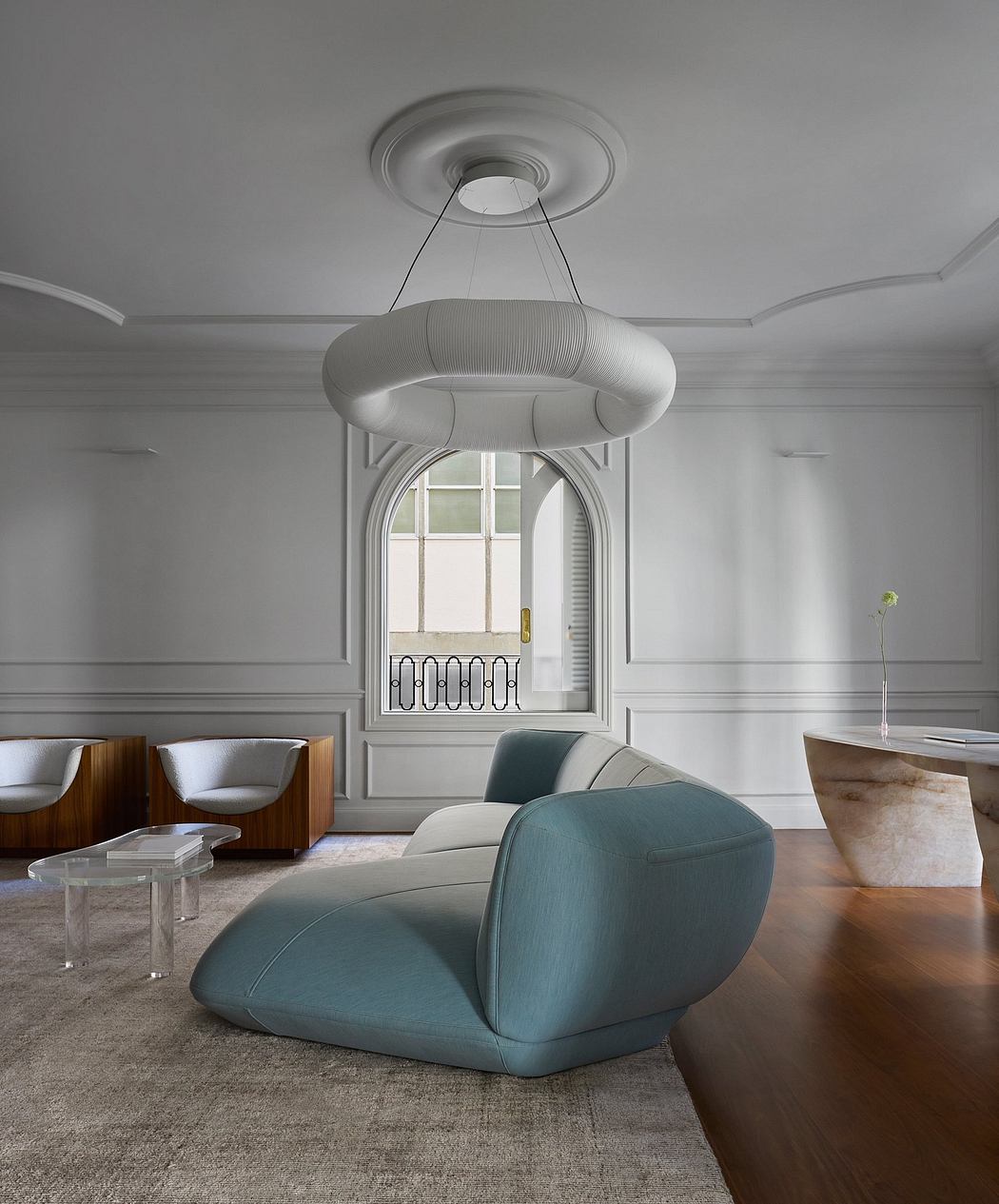 Elegant living room with plush turquoise sofa, ornate chandelier, and arched window.