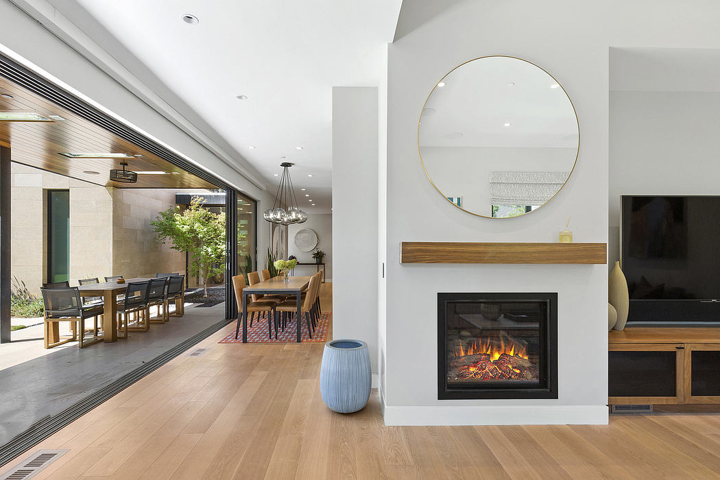 Modern living room with sleek fireplace, circular mirror, and wooden furniture.