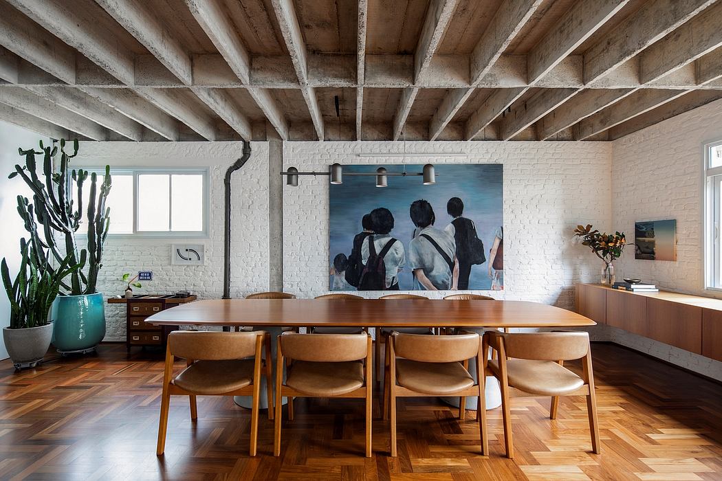Exposed wooden beams, brick walls, and a large modern painting adorn this industrial-style dining room.