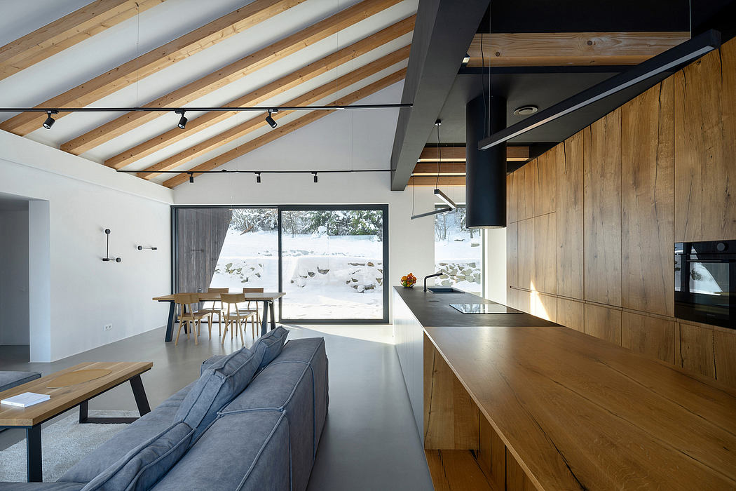 Spacious, modern cabin-style interior with exposed wooden beams, sleek kitchen, and large windows.