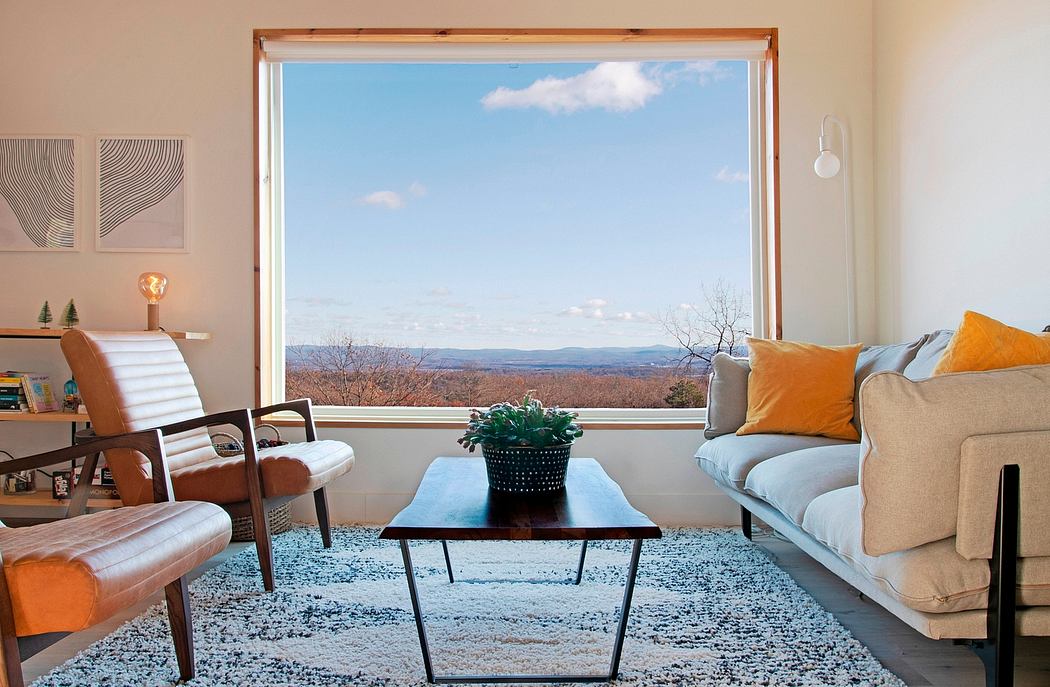Large window frames scenic mountain view in cozy living room with modern furnishings.