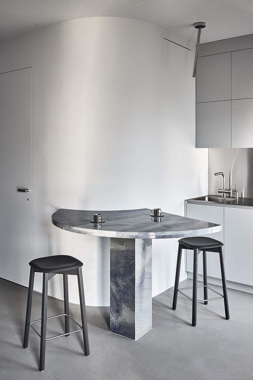 Minimalist kitchen design with sleek gray marble dining table and modern stools.