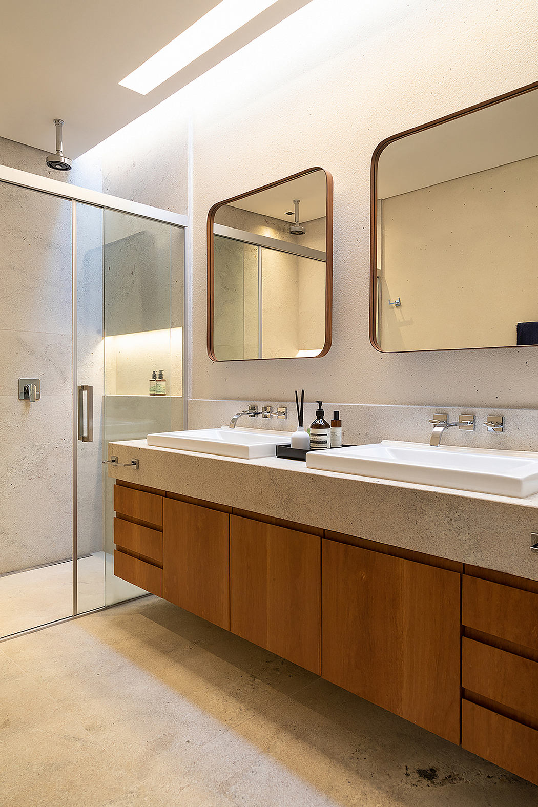 A modern bathroom with warm wood cabinetry, double sinks, and large mirrors.
