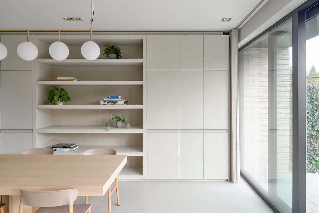 Minimalist dining area with built-in shelving, pendant lamps, and large sliding window.