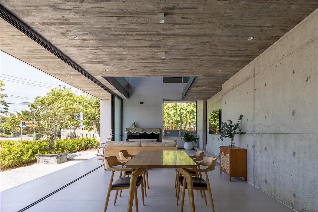 Minimalist concrete structure with wooden ceiling, large windows, and modern furniture.