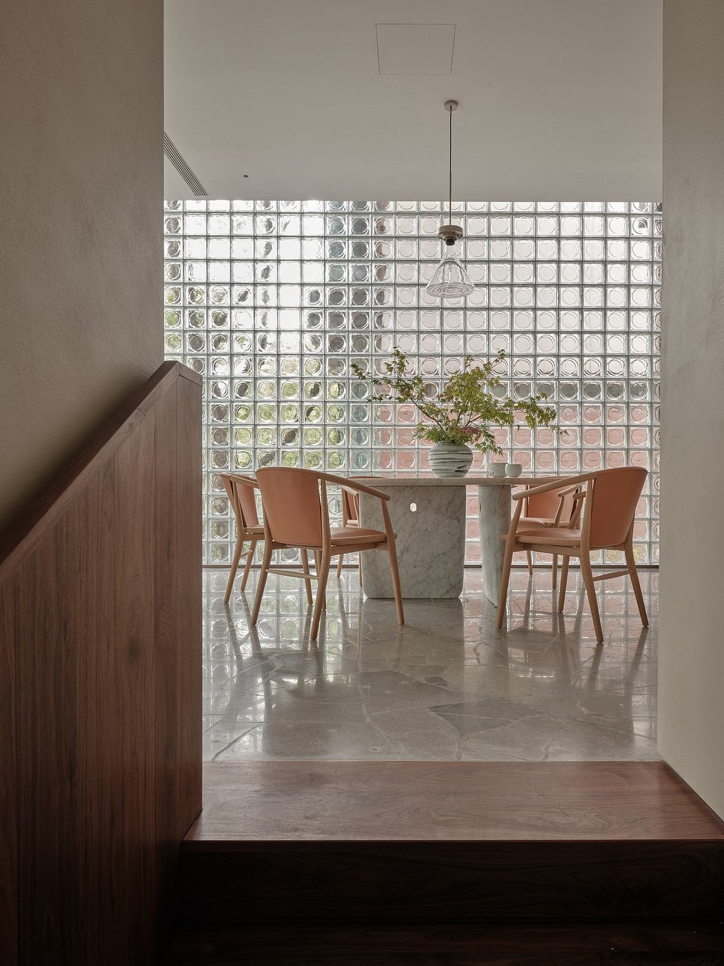 The dining area features a glass block wall, a marble table, and mid-century modern chairs.