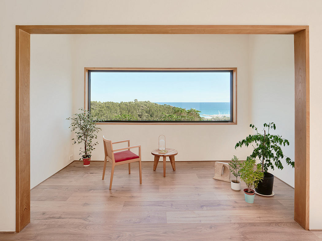 A spacious, light-filled room with a panoramic window overlooking lush greenery and the ocean.