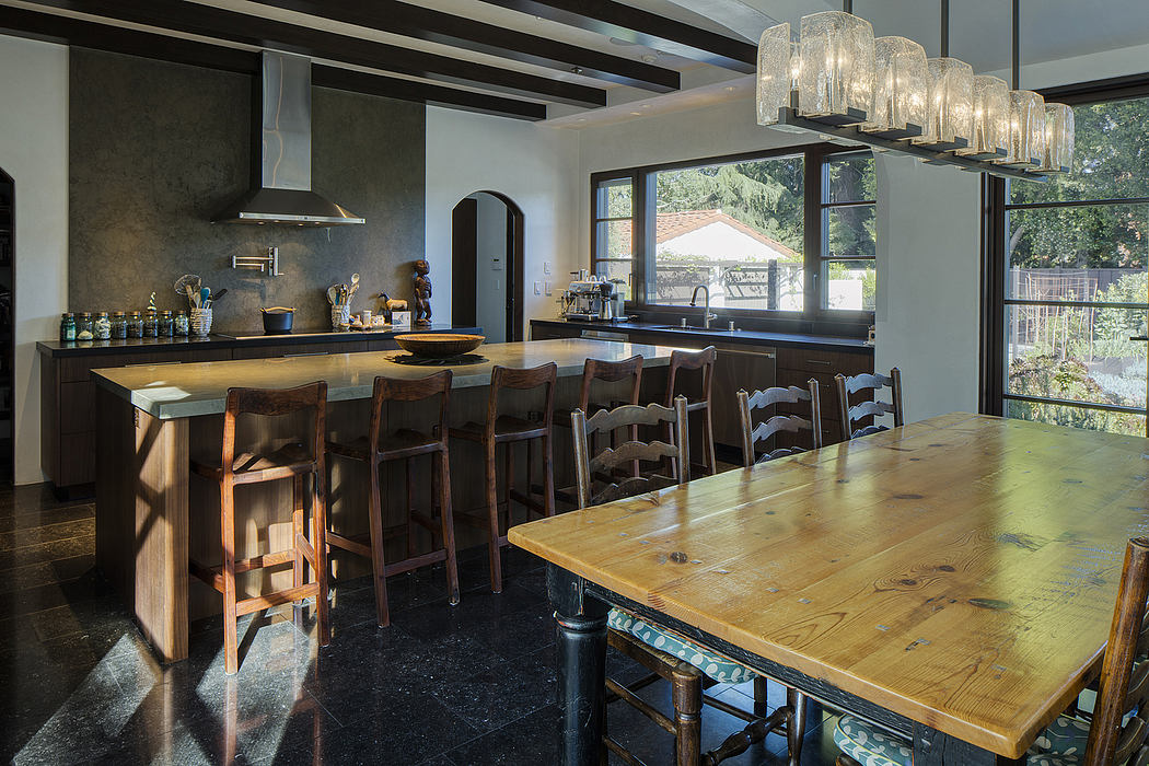 Spacious modern kitchen with rustic wooden table, sleek cabinetry, and ornate lighting.