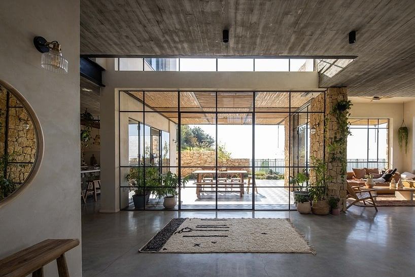 Minimalist concrete interior with large panoramic windows overlooking lush outdoor scenery.