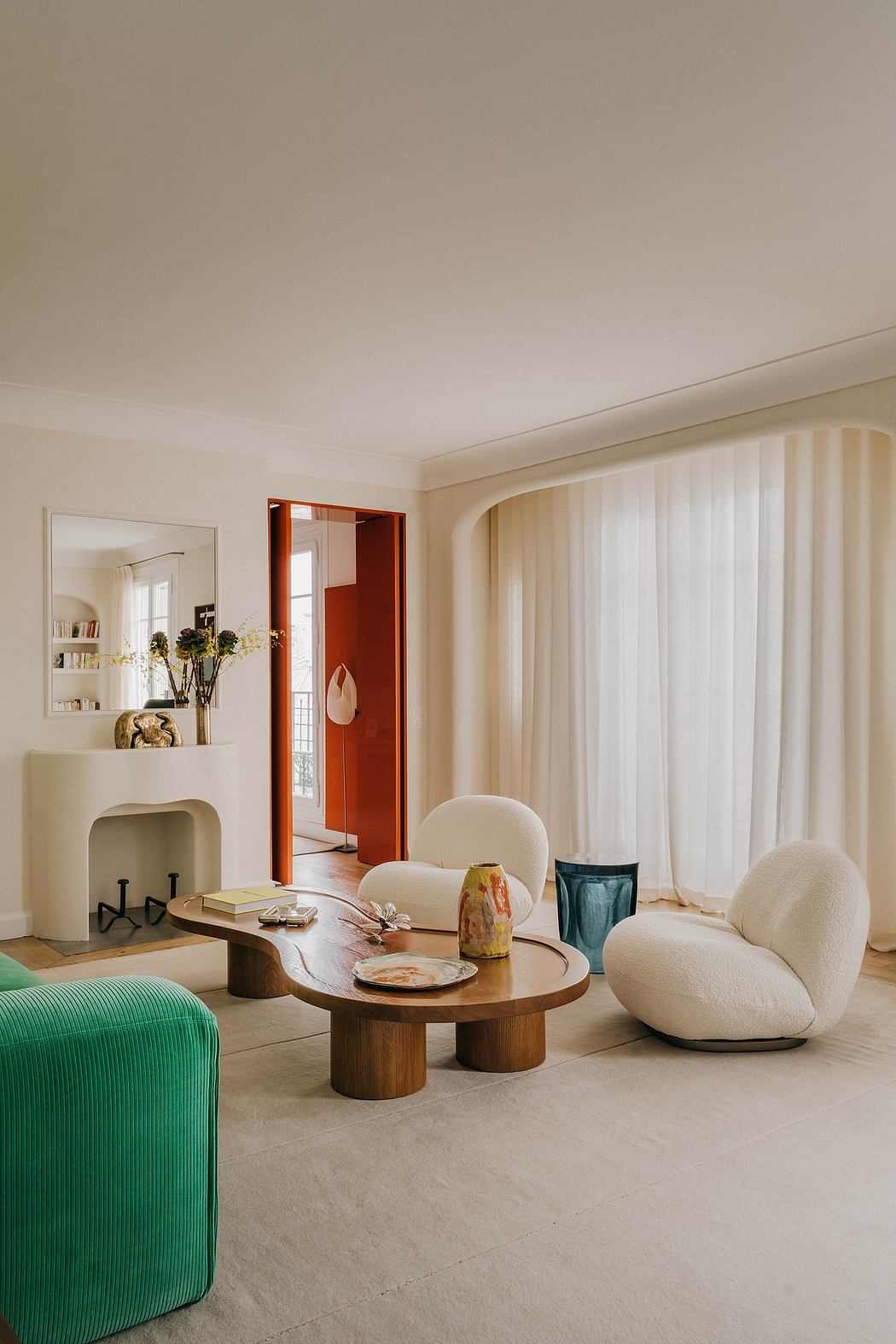 Modern living room with curved, plush seating, wood coffee table, and neutral palette.