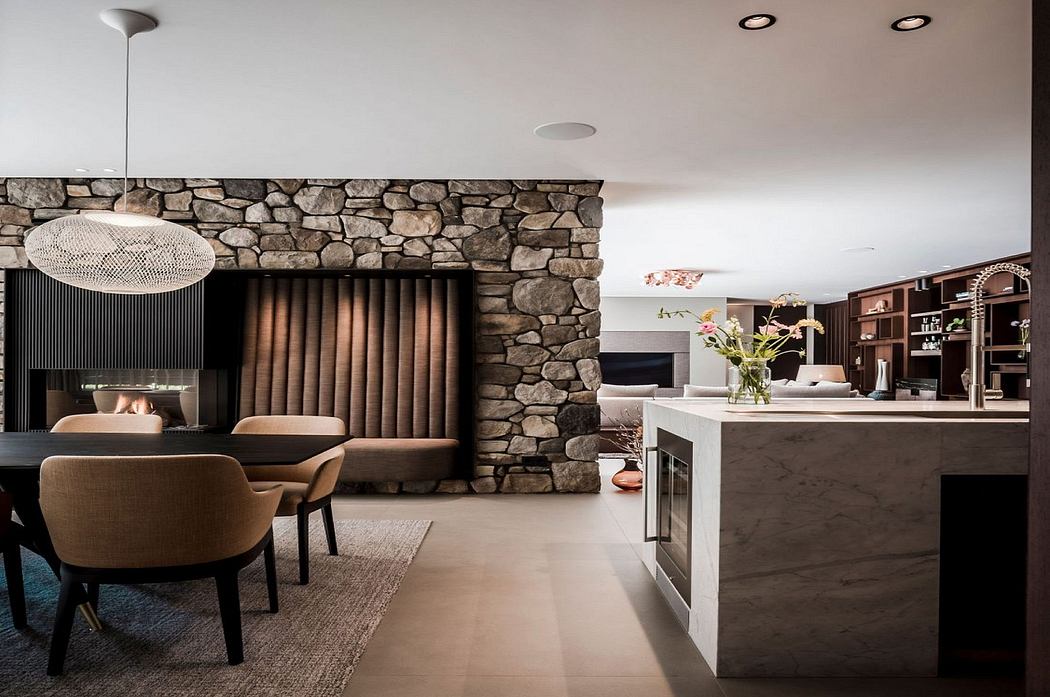Rustic stone wall contrasts with modern kitchen and dining area. Sleek marble countertop, recessed lighting.