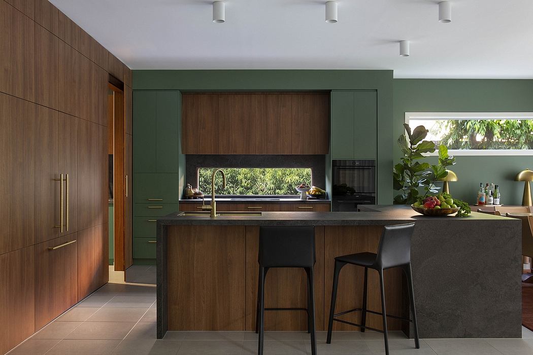 Modern, wood-paneled kitchen with green accent wall, black countertop, and recessed lighting.