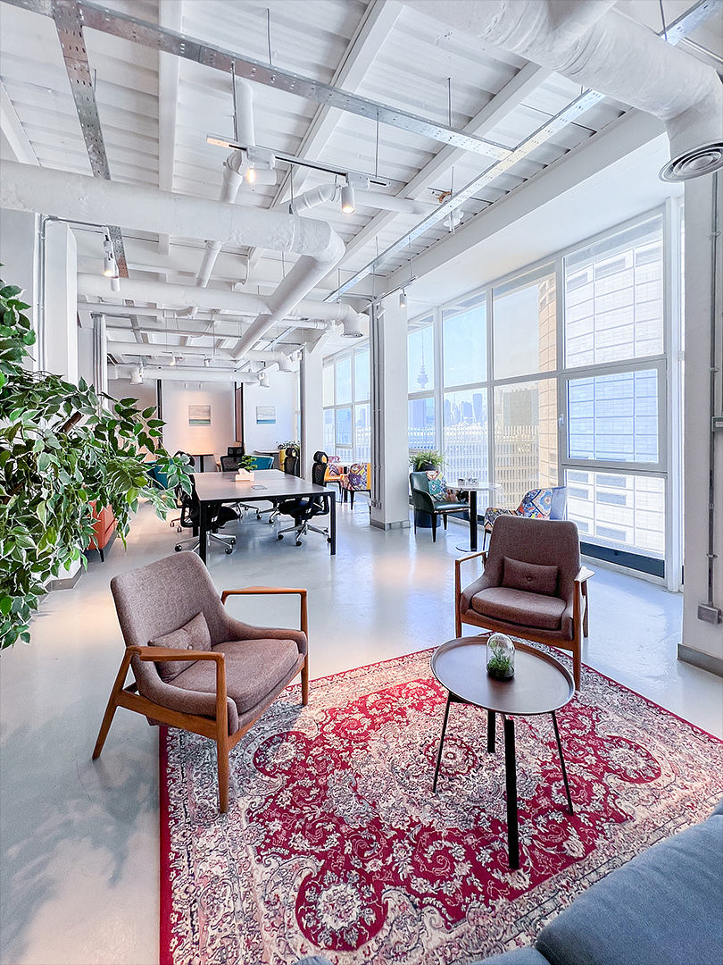 Bright, modern office space with exposed ceiling beams, large windows, and eclectic decor.