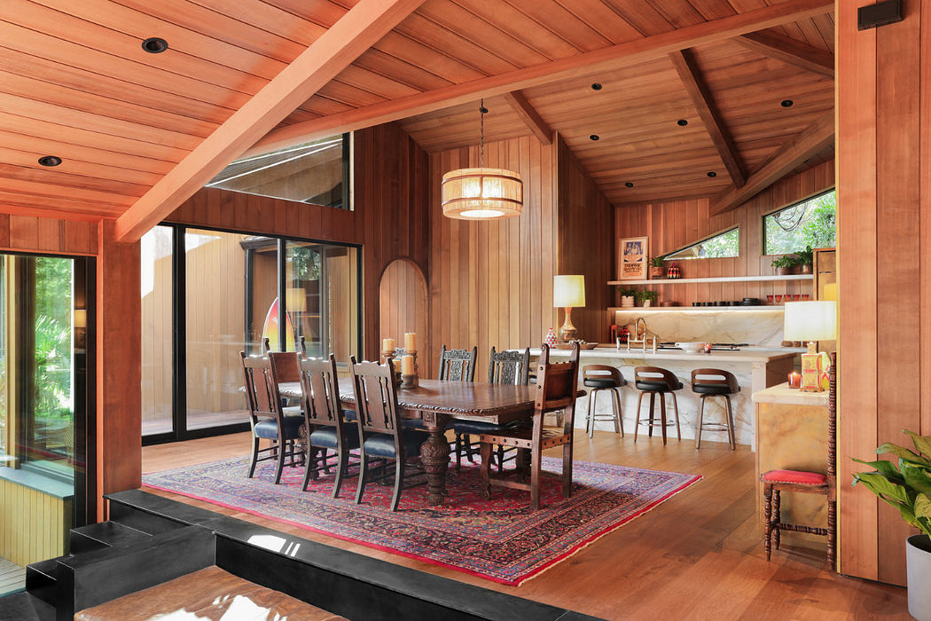 Rustic wooden interior with exposed beams, modern kitchen, and dining table with ornate chairs.