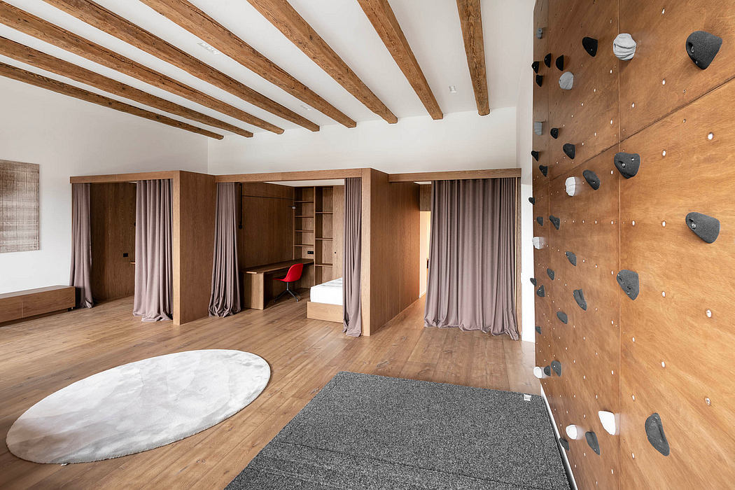 Spacious loft with exposed wood beams, curtained alcoves, and a climbing wall feature.