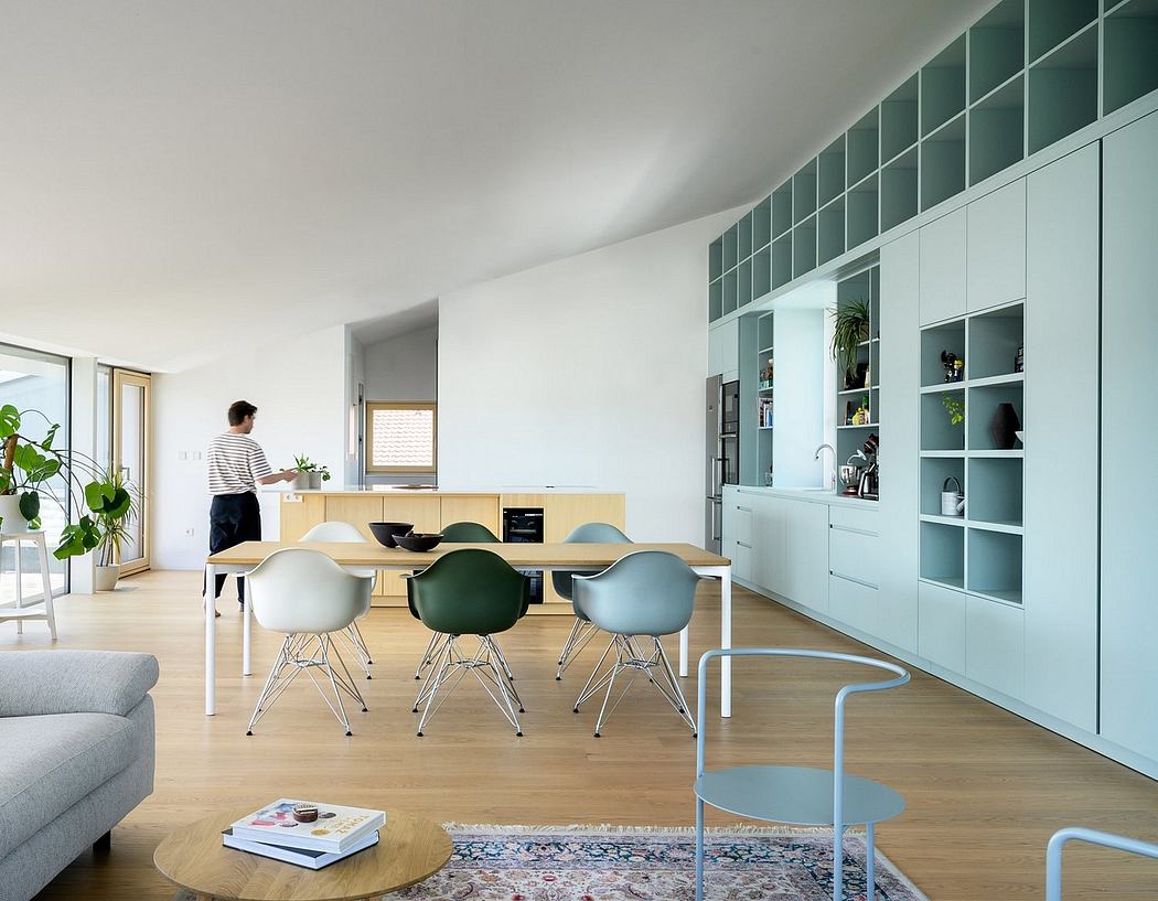 Minimalist open-plan kitchen and dining room with wooden table, Eames-style chairs, and built-in cabinetry.