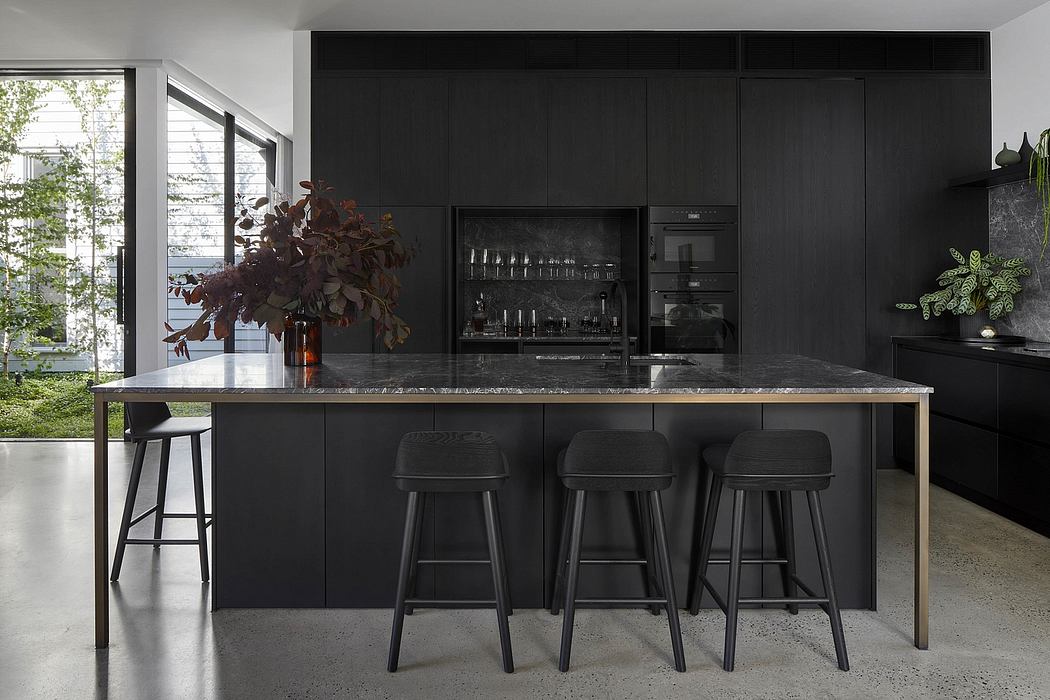 Sleek, modern kitchen with dark cabinetry, marble countertop, and minimalist bar stools.