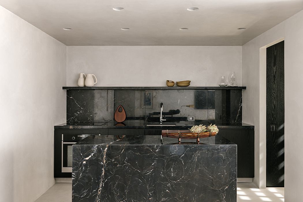 Sleek modern kitchen with black marble countertops, open shelving, and recessed lighting.