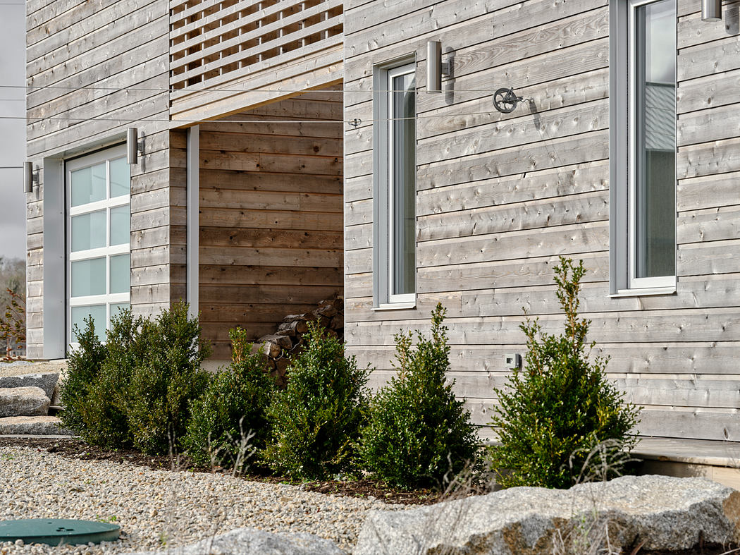 Rustic modern facade with wooden siding, glass windows, and landscaped greenery.