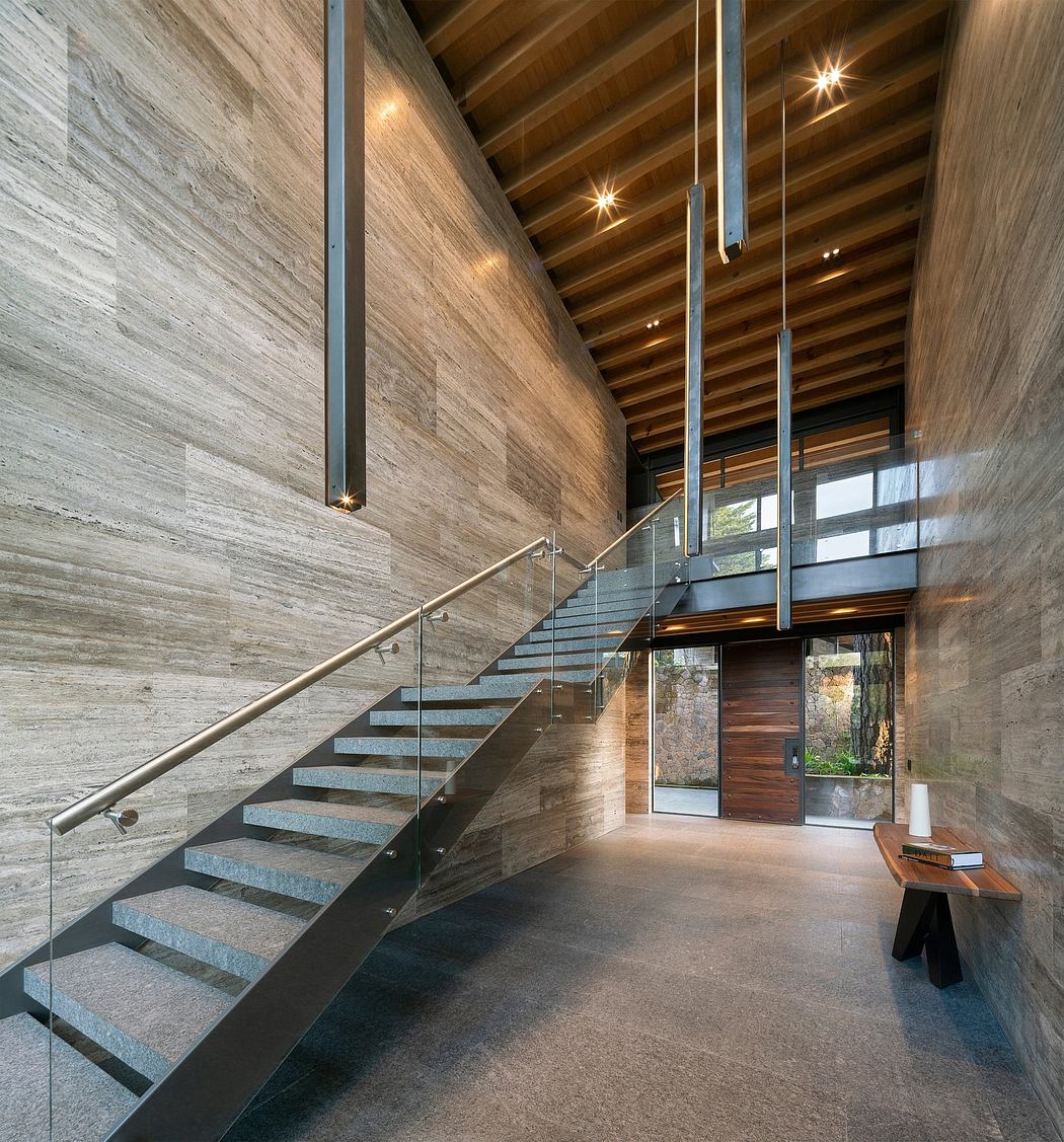 Sleek modern entryway featuring a grand staircase, wood-paneled ceilings, and glass walls.