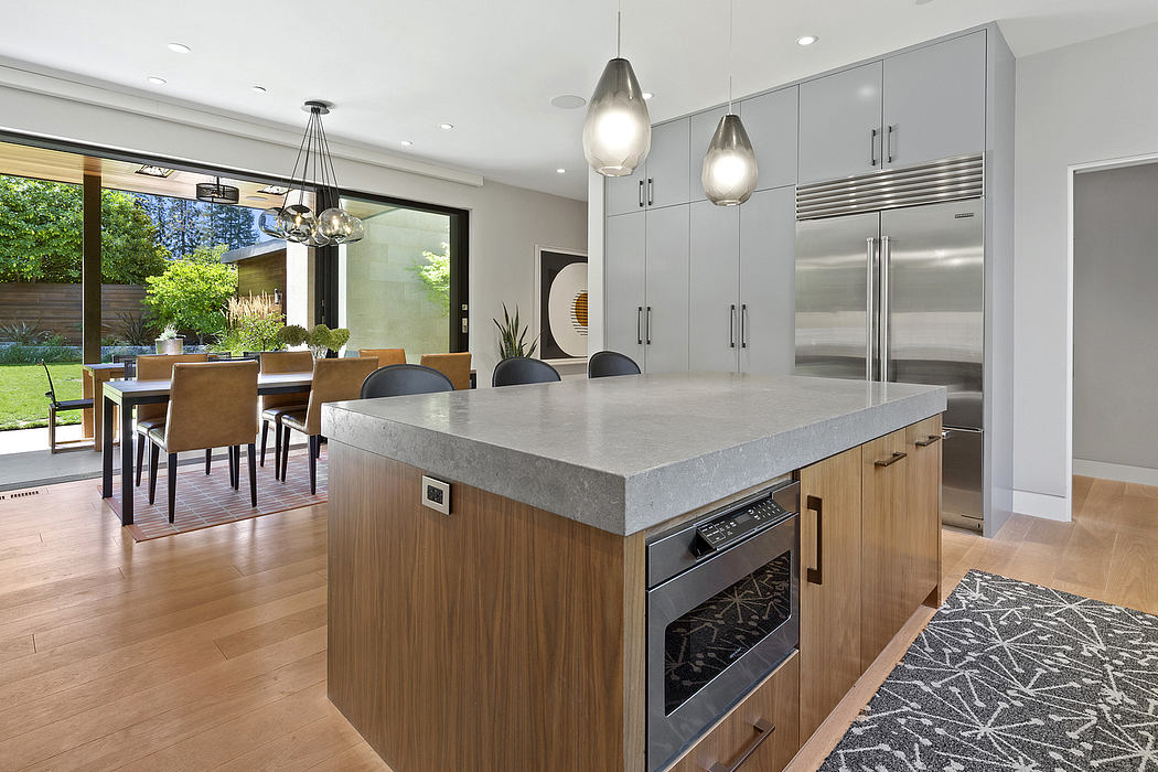 Sleek and modern kitchen design with concrete countertops, wood cabinetry, and pendant lighting.