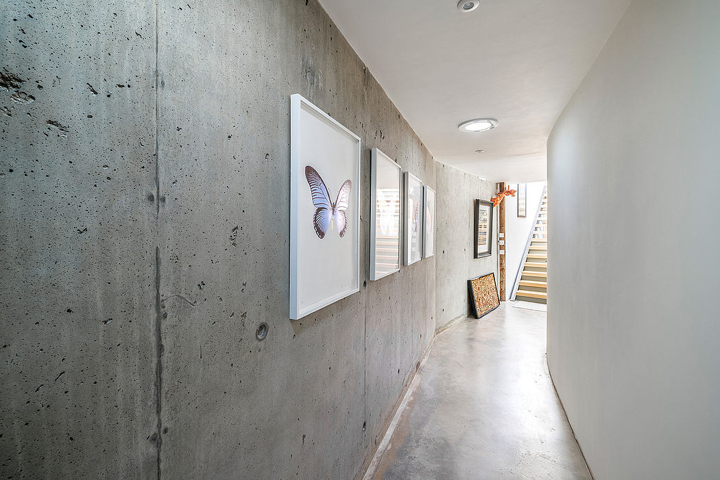 Minimalist interior featuring concrete walls, framed artwork, and a staircase.