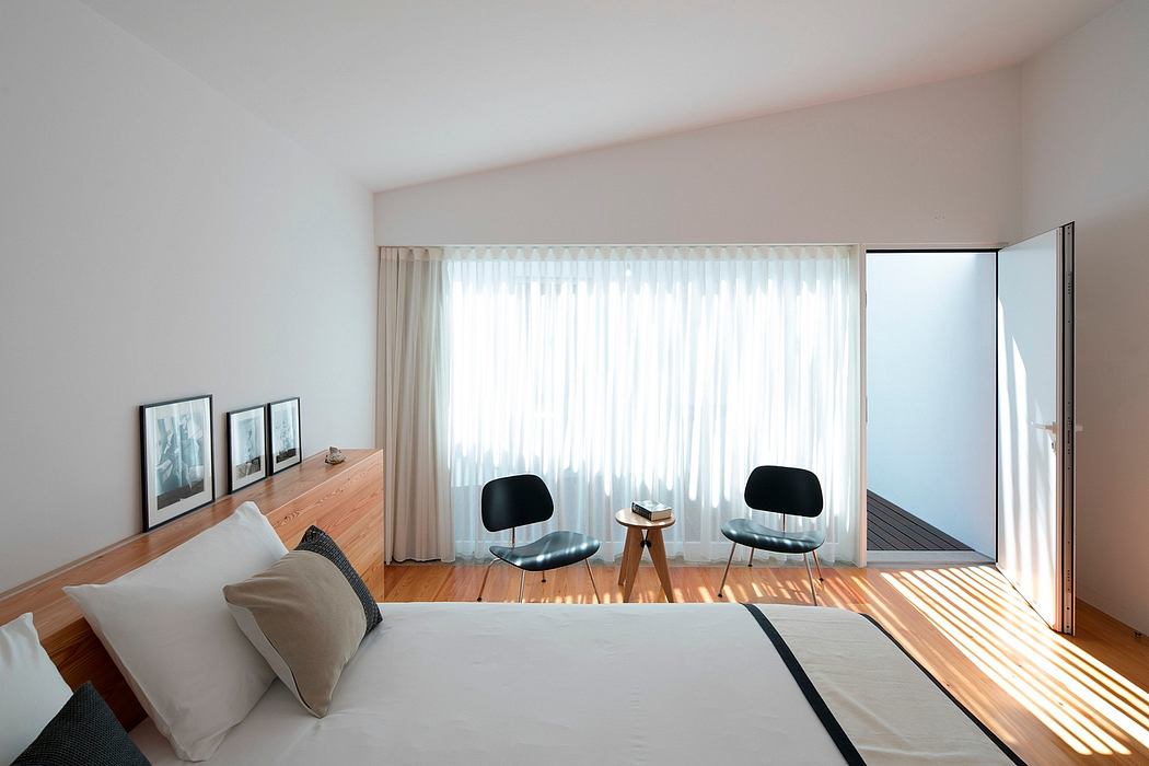 A minimalist bedroom with wooden floors, large windows, and tasteful modern furniture.