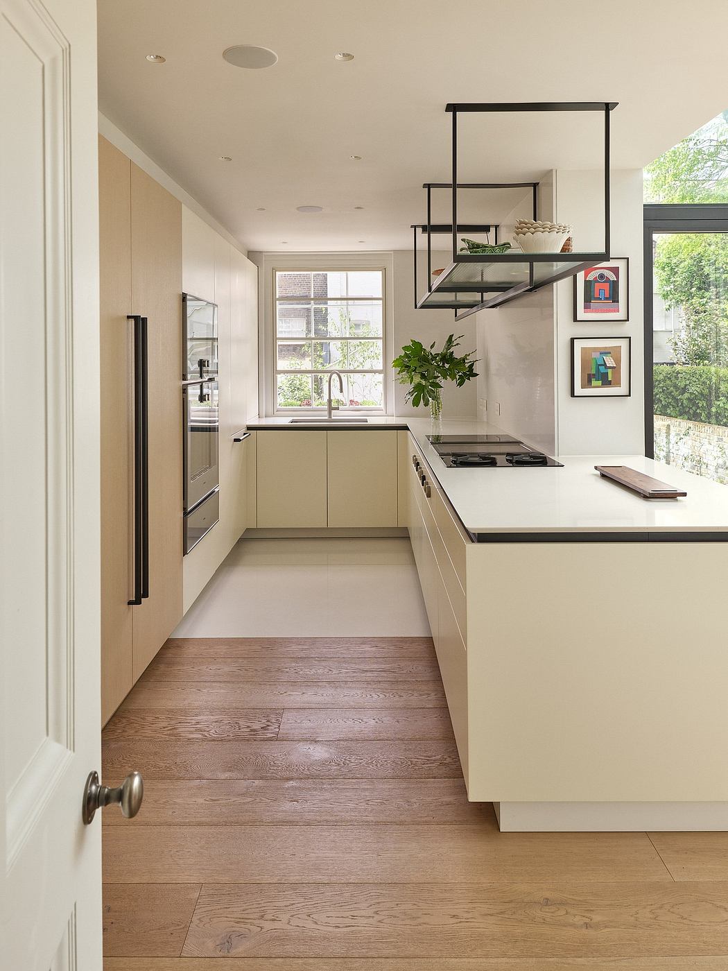 Sleek modern kitchen with recessed lighting, floating shelves, and wood flooring.