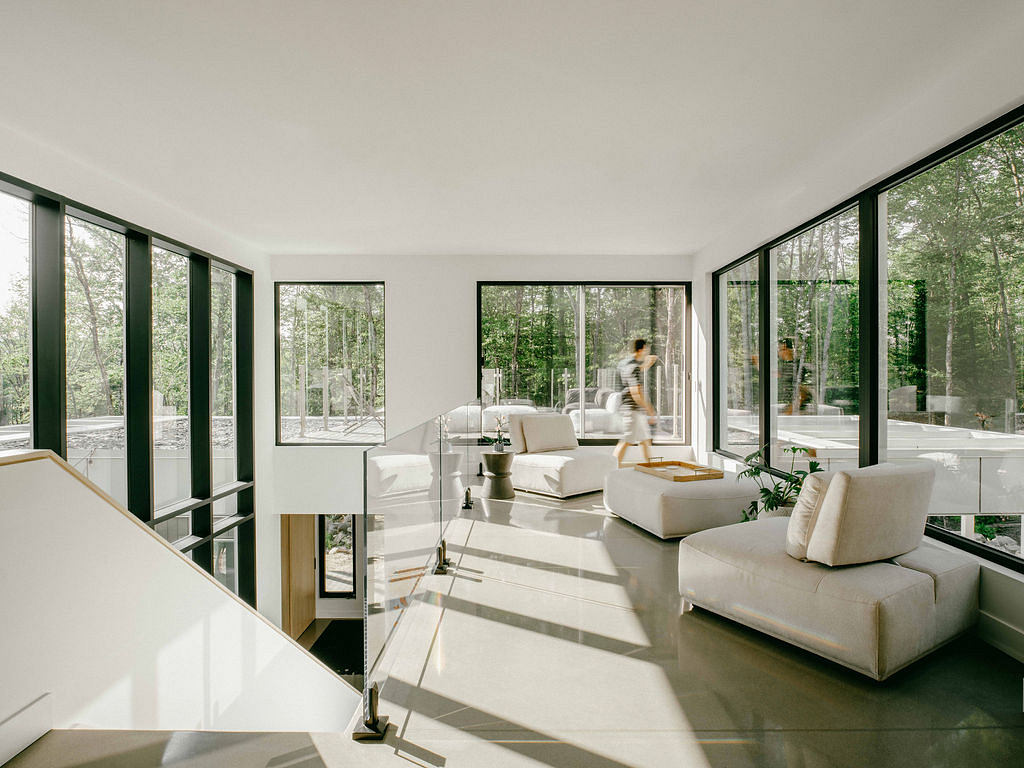 Spacious, light-filled living room with expansive windows overlooking lush greenery.