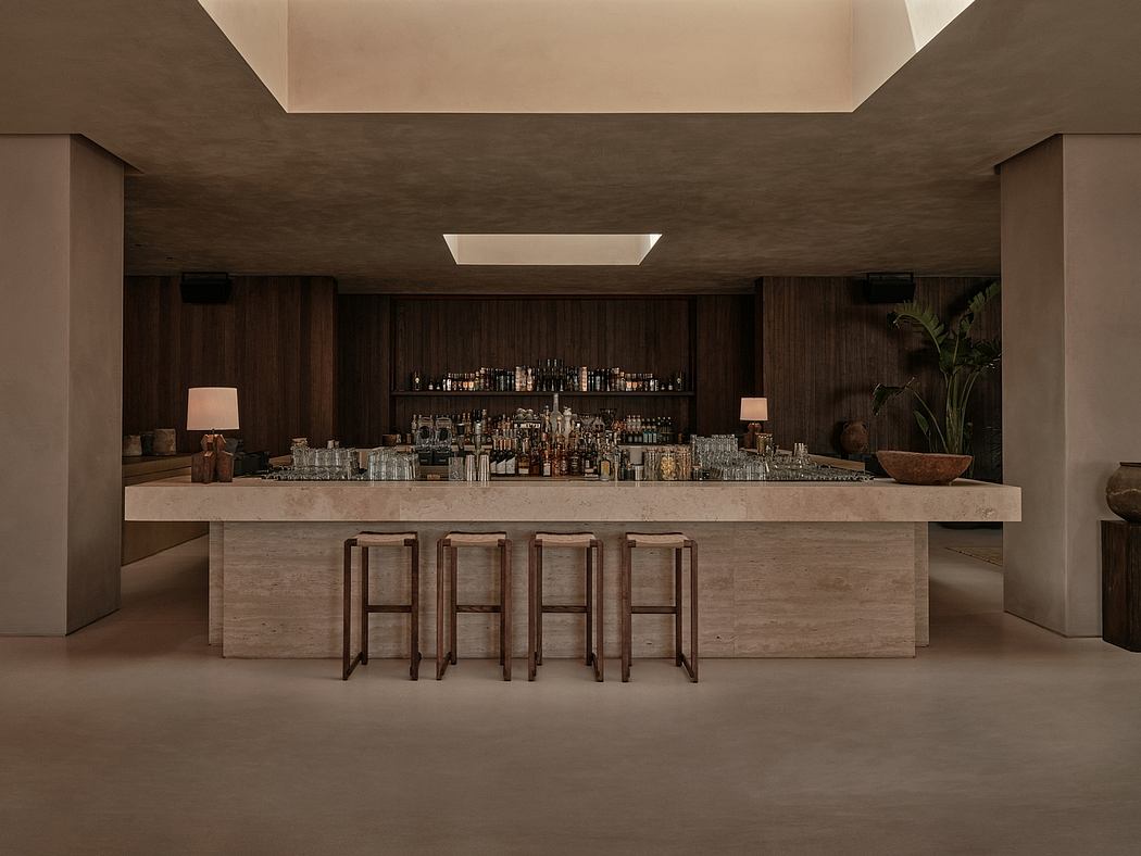 A sleek, modern bar with a long concrete counter, minimalist lighting, and an extensive liquor selection.